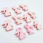 Pastel pink bunny stud blanks showing finished paint filled black eyelashes on two studs, with the rest shown as supplied with protective film