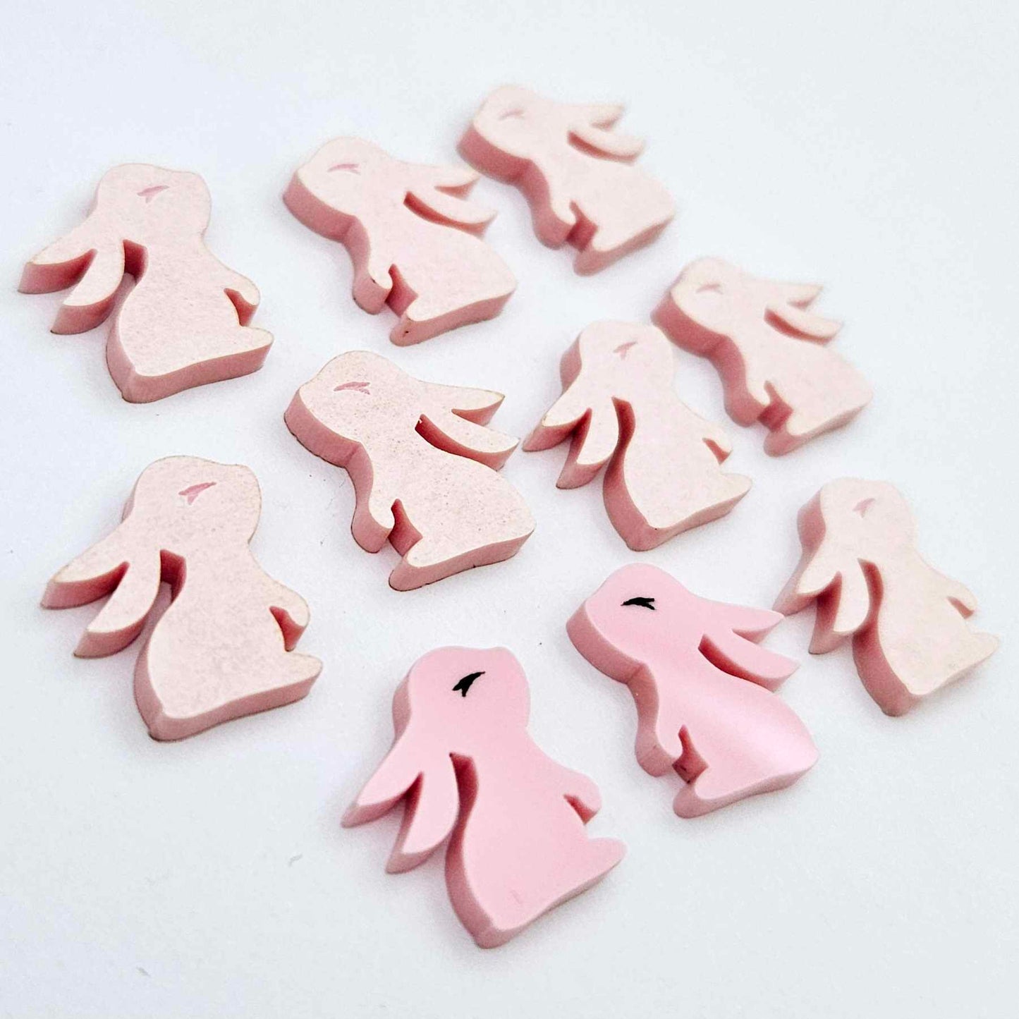 Pastel pink bunny stud blanks showing finished paint filled black eyelashes on two studs, with the rest shown as supplied with protective film