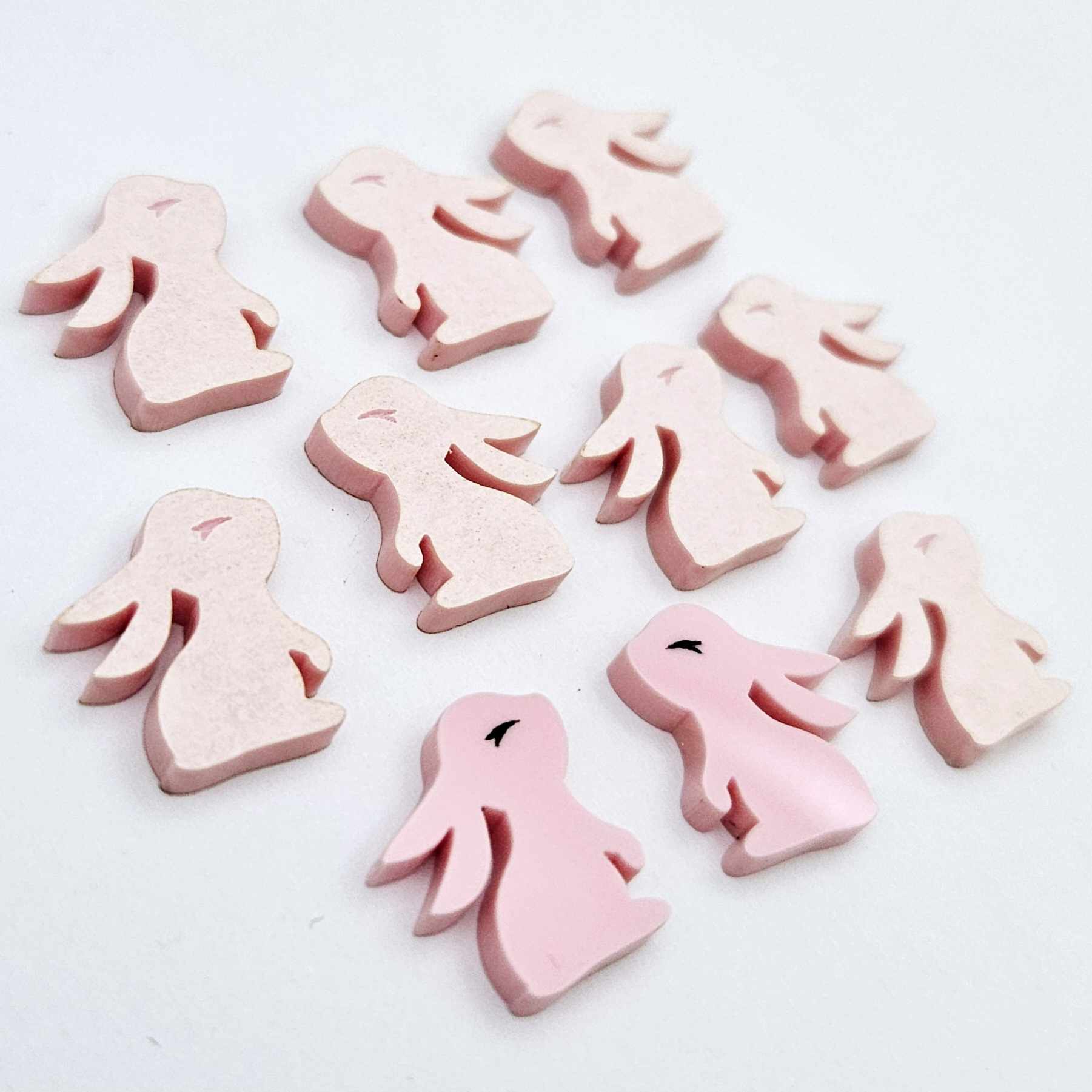 Pastel pink bunny stud blanks showing finished paint filled black eyelashes on two studs, with the rest shown as supplied with protective film