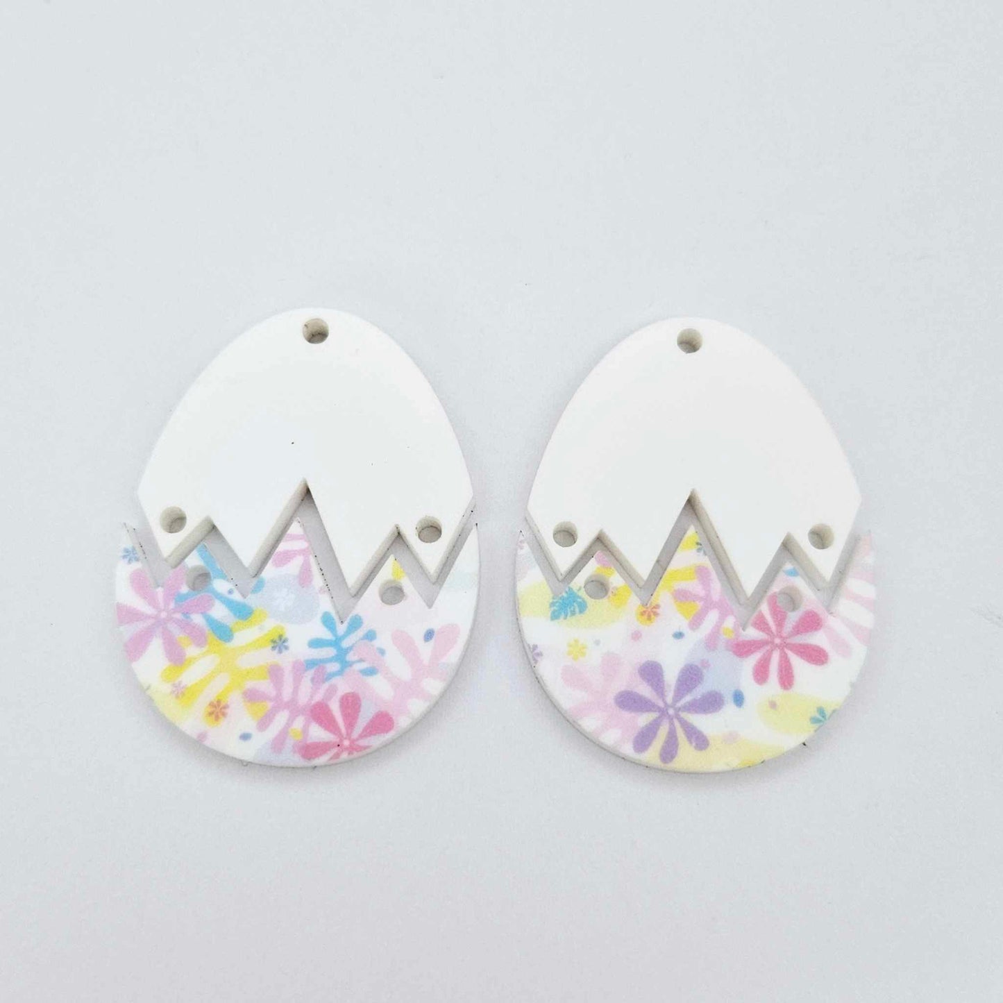Two cracked egg acrylic earring blanks unassembled, white top halves and pastel pop UV printed bottom halves