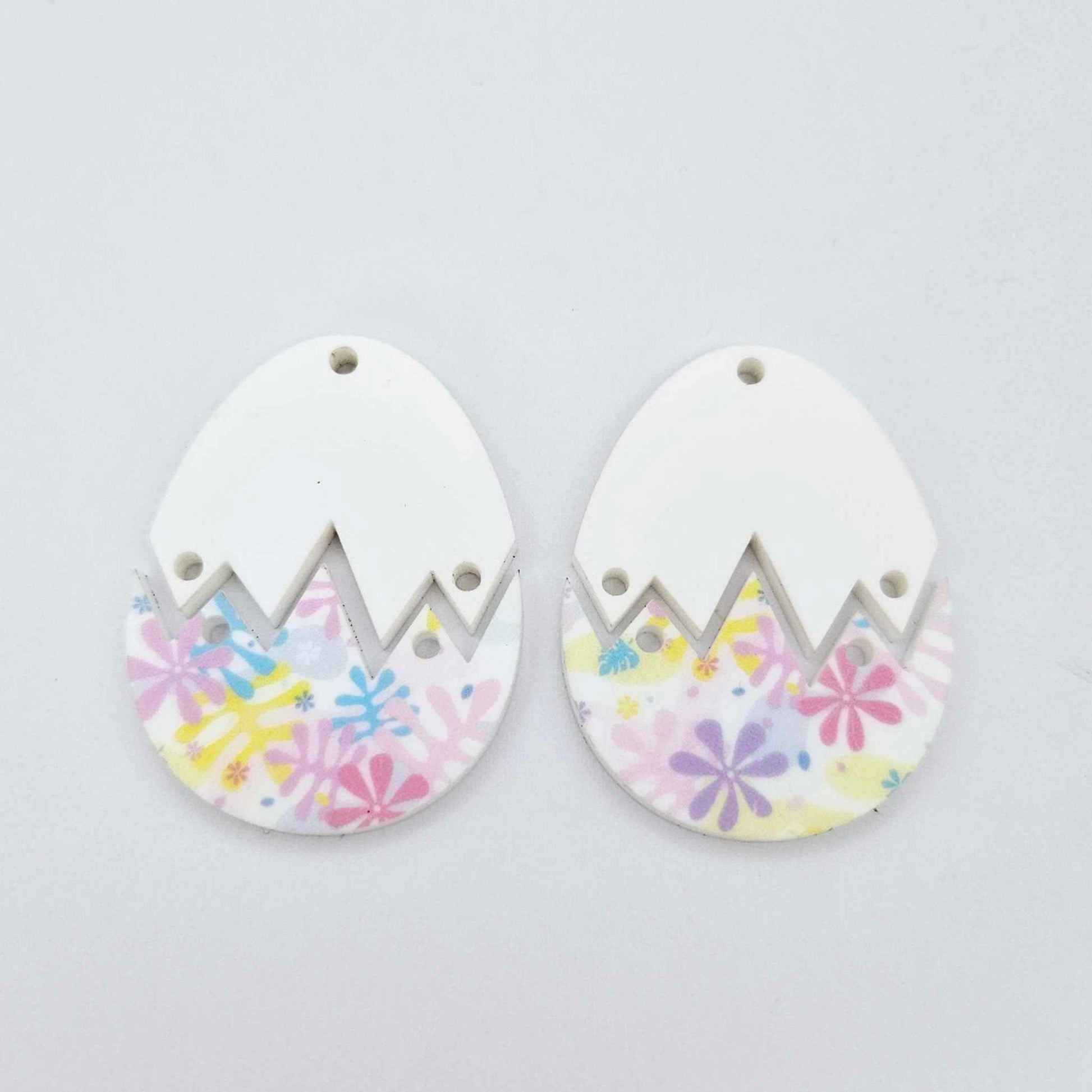 Two cracked egg acrylic earring blanks unassembled, white top halves and pastel pop UV printed bottom halves