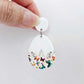 Assembled cracked egg acrylic dangle earring blank with white top and butterfly UV printed bottom, hanging from a 14mm white earring topper