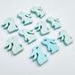 Pastel aqua bunny stud blanks showing finished paint filled black eyelashes on two studs, with the rest shown as supplied with protective film