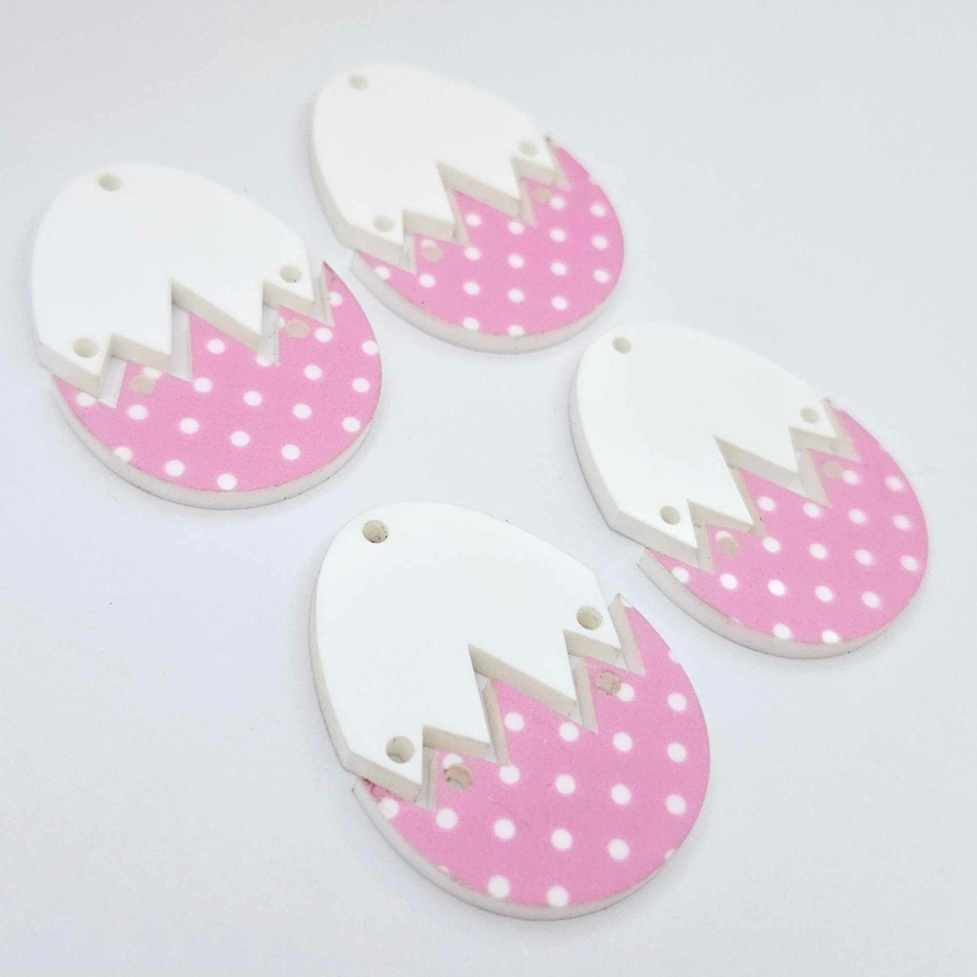 Four cracked egg earring blanks unassembled, white top halves and pastel pink polka dot UV printed bottom halves