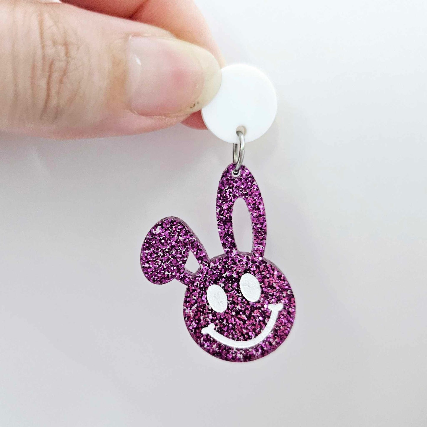 38mm purple glitter acrylic bunny dangle earring blank hanging from a 14mm white acrylic topper, bunny head with floppy ear and paint filled smiley face