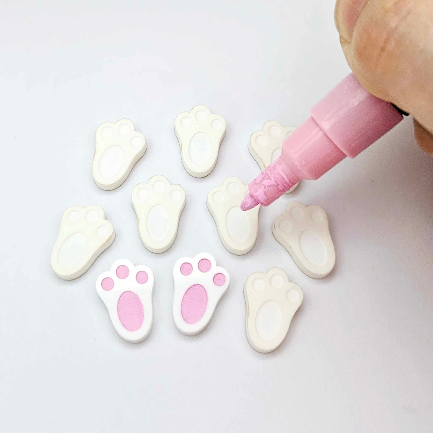 white bunny paw print stud blanks showing two paint filled pink and several unpainted pieces, with a Light Pink Posca paint pen included in the image