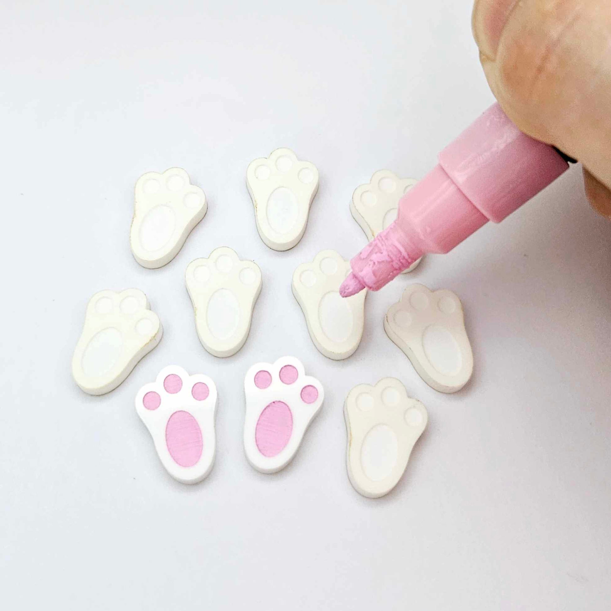 white bunny paw print stud blanks showing two paint filled pink and several unpainted pieces, with a Light Pink Posca paint pen included in the image