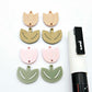 Two-piece tulip acrylic dangle blanks in dusty pale pink and olive green, paint filled white on one pair with remaining pair unfilled, shown with a white Posca paint pen