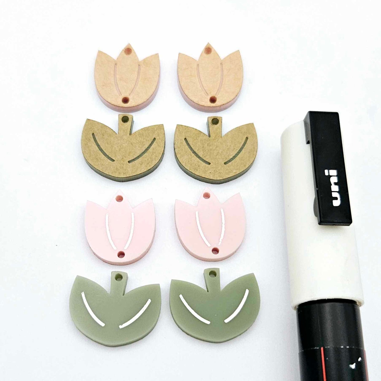 Two-piece tulip acrylic dangle blanks in dusty pale pink and olive green, paint filled white on one pair with remaining pair unfilled, shown with a white Posca paint pen