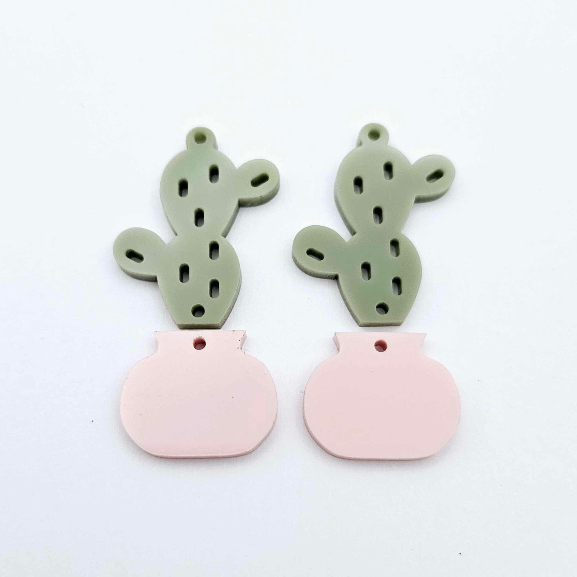 Two-piece cactus dangle blanks in olive green and strawberry milkshake pink, shown unassembled with cactus top and pot bottom pieces laid flat