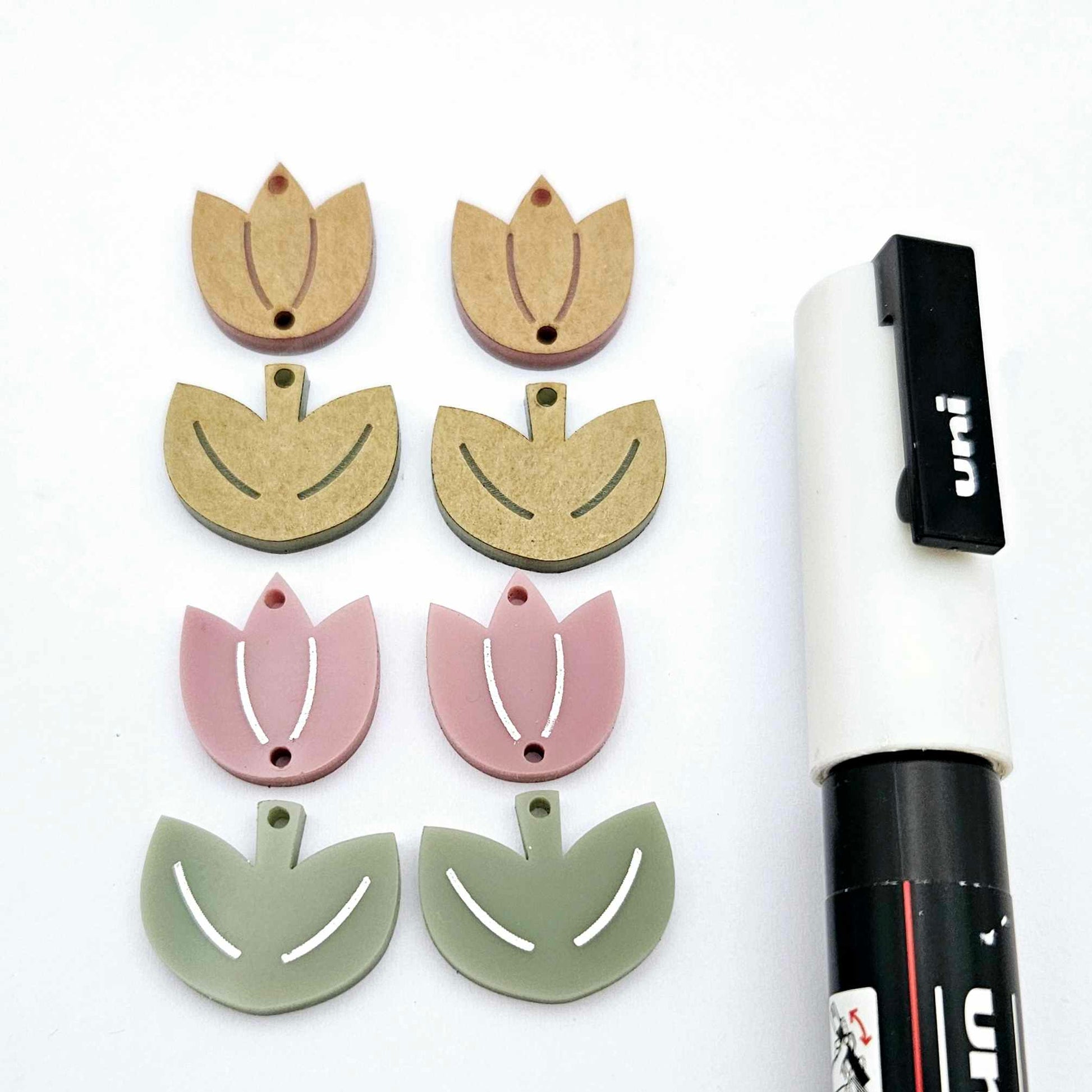 Two-piece tulip dangle blanks in dusty rose and olive green, paint filled white on one pair with remaining pair unfilled, shown with a white Posca paint pen