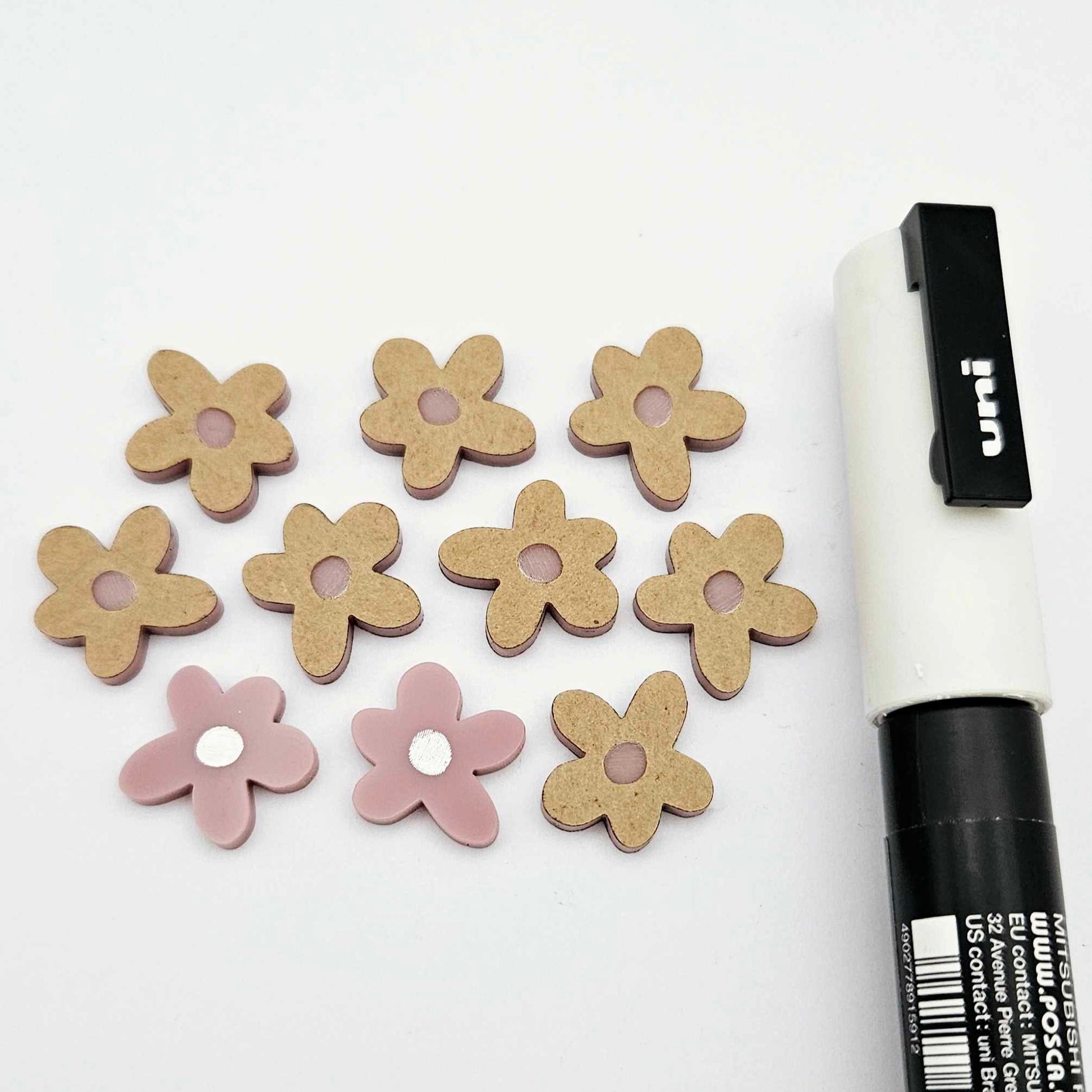 16mm dusty rose organic flower stud blanks showing paint filled white example and unfilled pieces with protective film, pictured with a white Posca paint pen