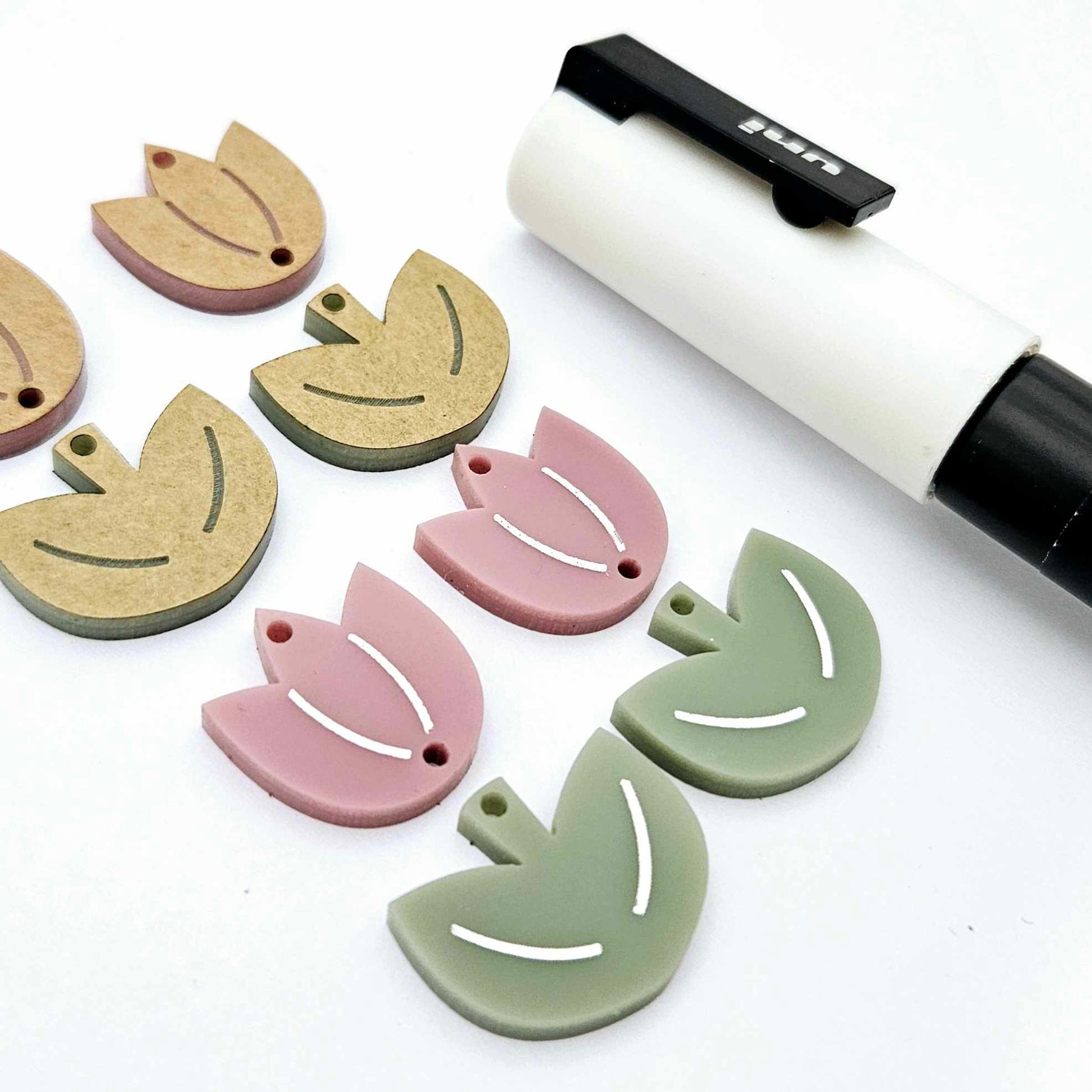 Two-piece tulip dangle blanks in dusty rose and olive green, paint filled white on one pair with remaining pair unfilled, shown with a white Posca paint pen