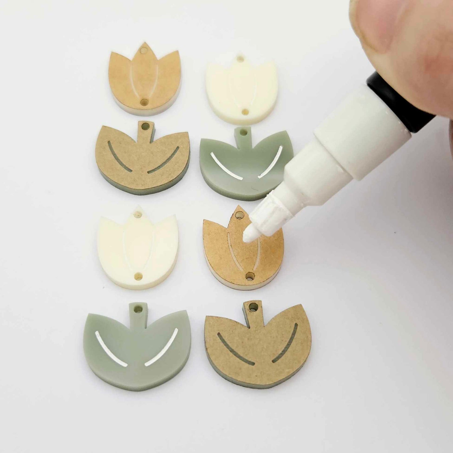 Two-piece tulip acrylic dangle blanks in cream and olive green, paint filled white on one pair with remaining pair unfilled, shown with a white Posca paint pen