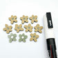 16mm olive green organic flower stud blanks showing paint filled white example and unfilled pieces with protective film, pictured with a white Posca paint pen