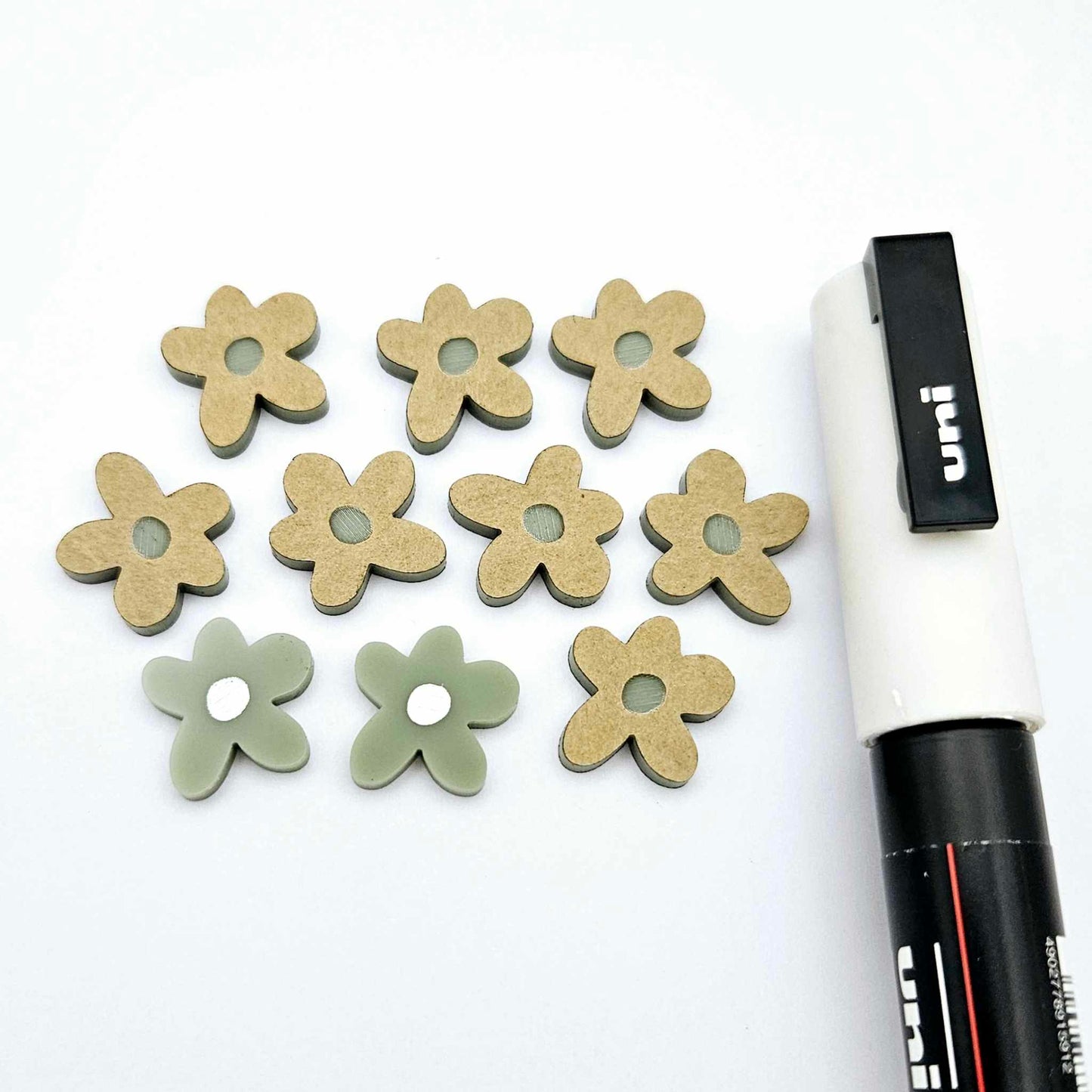 16mm olive green organic flower stud blanks showing paint filled white example and unfilled pieces with protective film, pictured with a white Posca paint pen