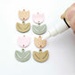 Two-piece tulip acrylic dangle blanks in dusty pale pink and olive green, paint filled white on one pair with remaining pair unfilled, shown with a white Posca paint pen