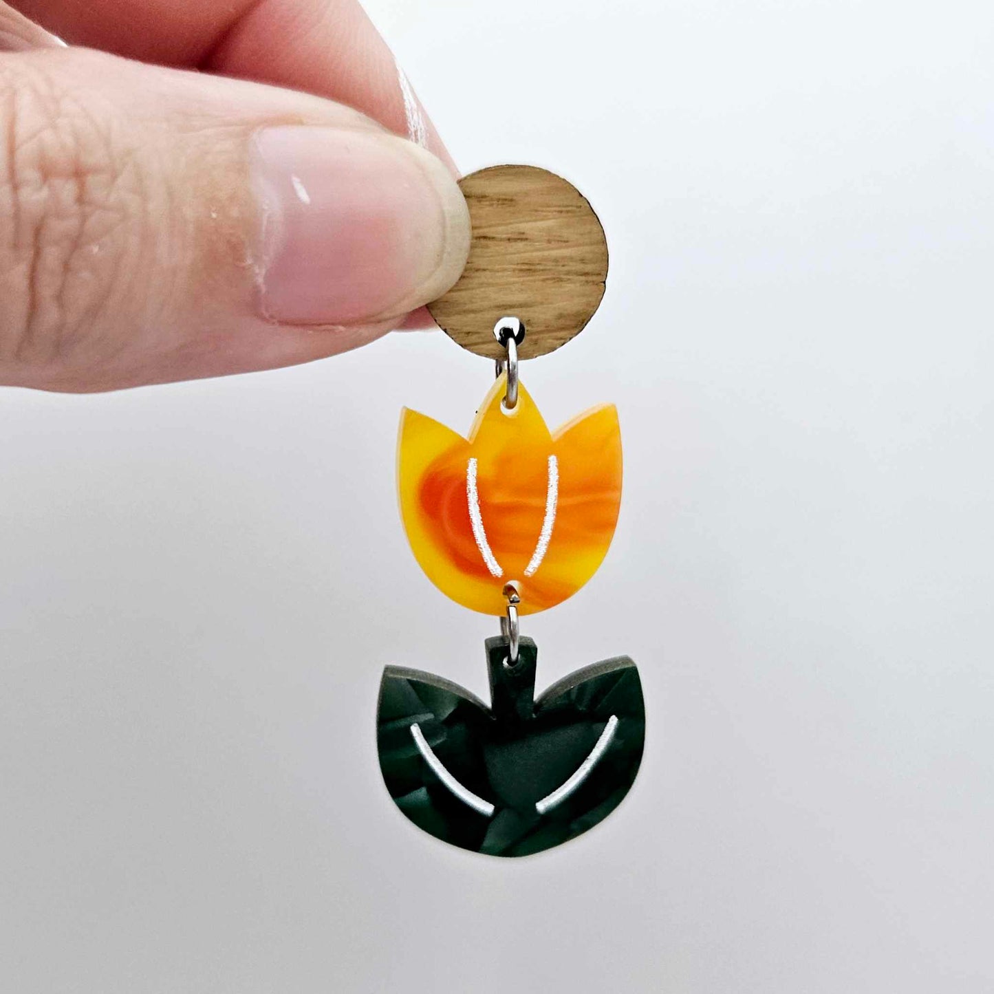Assembled orange artist swirl and green mineral acrylic tulip dangle hanging from a 14mm oak wood topper, engraved detail paint filled white