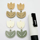 Two-piece tulip acrylic dangle blanks in cream and olive green, paint filled white on one pair with remaining pair unfilled, shown with a white Posca paint pen