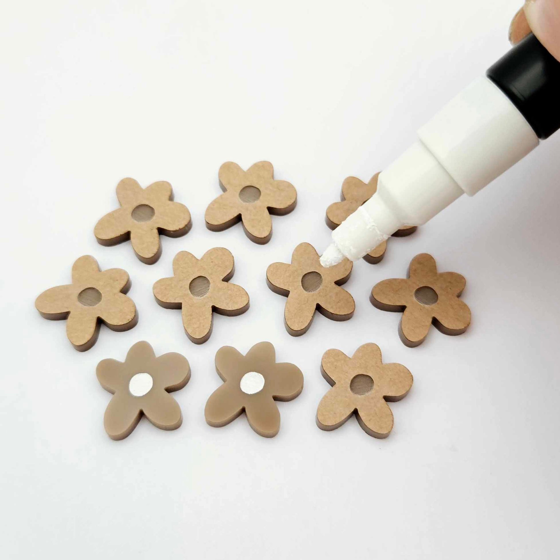 16mm iced coffee brown organic flower stud blanks showing paint filled white example and unfilled pieces with protective film, pictured with a white Posca paint pen
