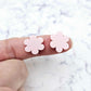 Two 14mm strawberry milkshake pink flower stud blanks, shown on a finger for size reference