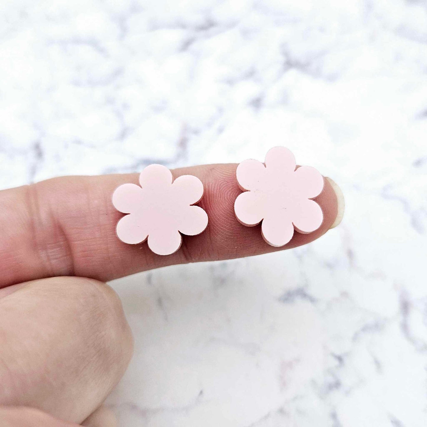 Two 14mm strawberry milkshake pink flower stud blanks, shown on a finger for size reference