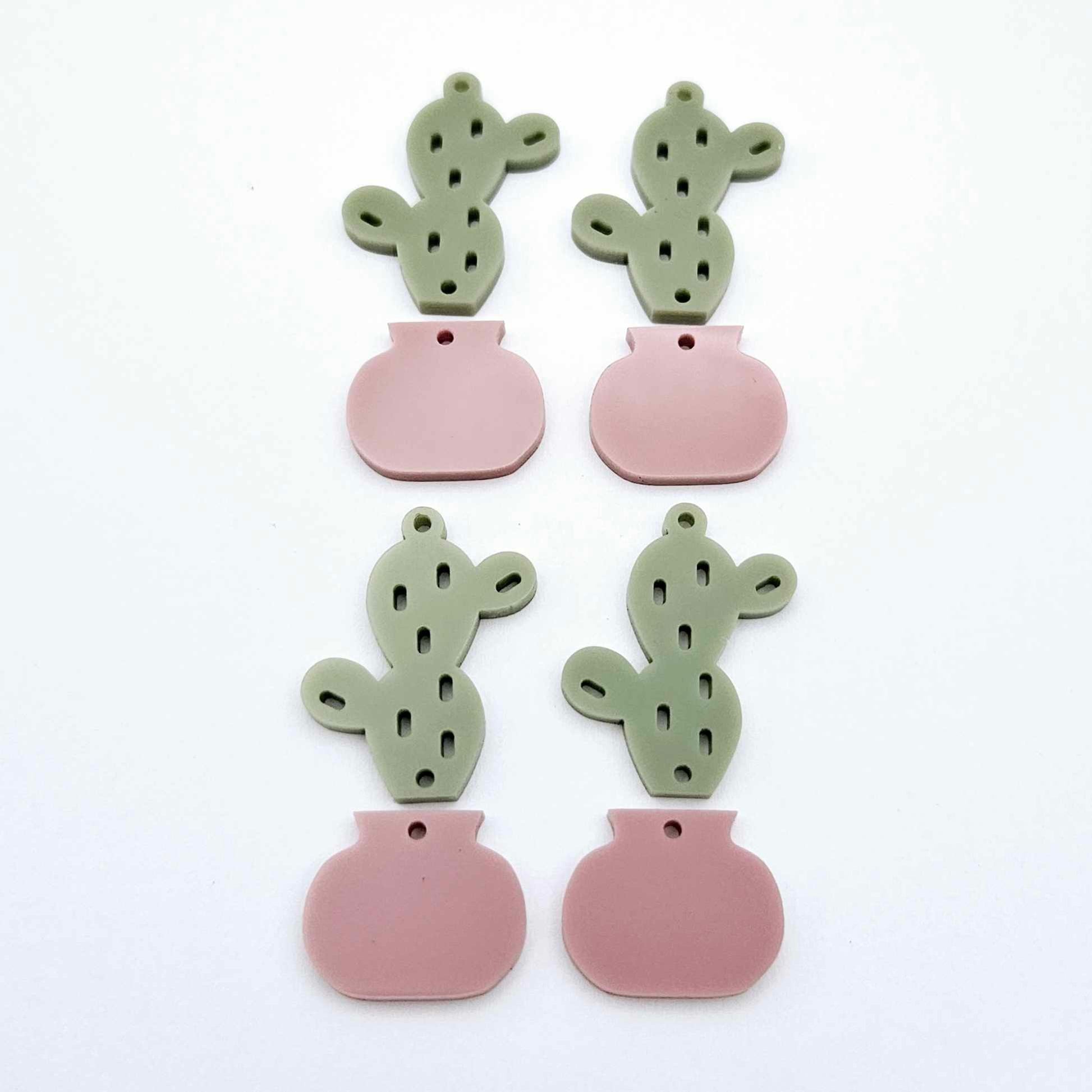 Two-piece acrylic cactus dangle blanks in olive green and dusty rose pink, shown unassembled with cactus top and pot bottom pieces laid flat
