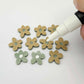 16mm olive green organic flower stud blanks showing paint filled white example and unfilled pieces with protective film, pictured with a white Posca paint pen