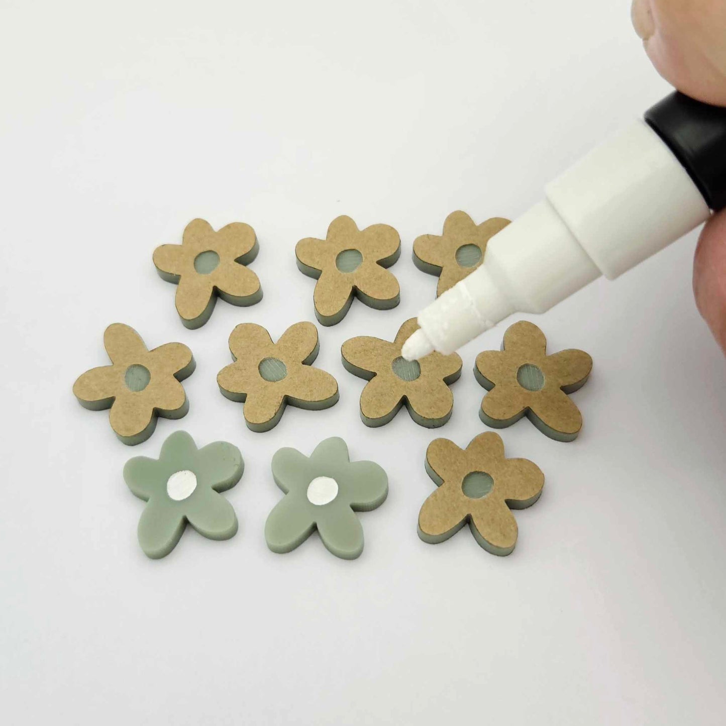 16mm olive green organic flower stud blanks showing paint filled white example and unfilled pieces with protective film, pictured with a white Posca paint pen