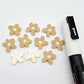 16mm cream organic flower stud blanks showing paint filled white example and unfilled pieces with protective film, pictured with a white Posca paint pen