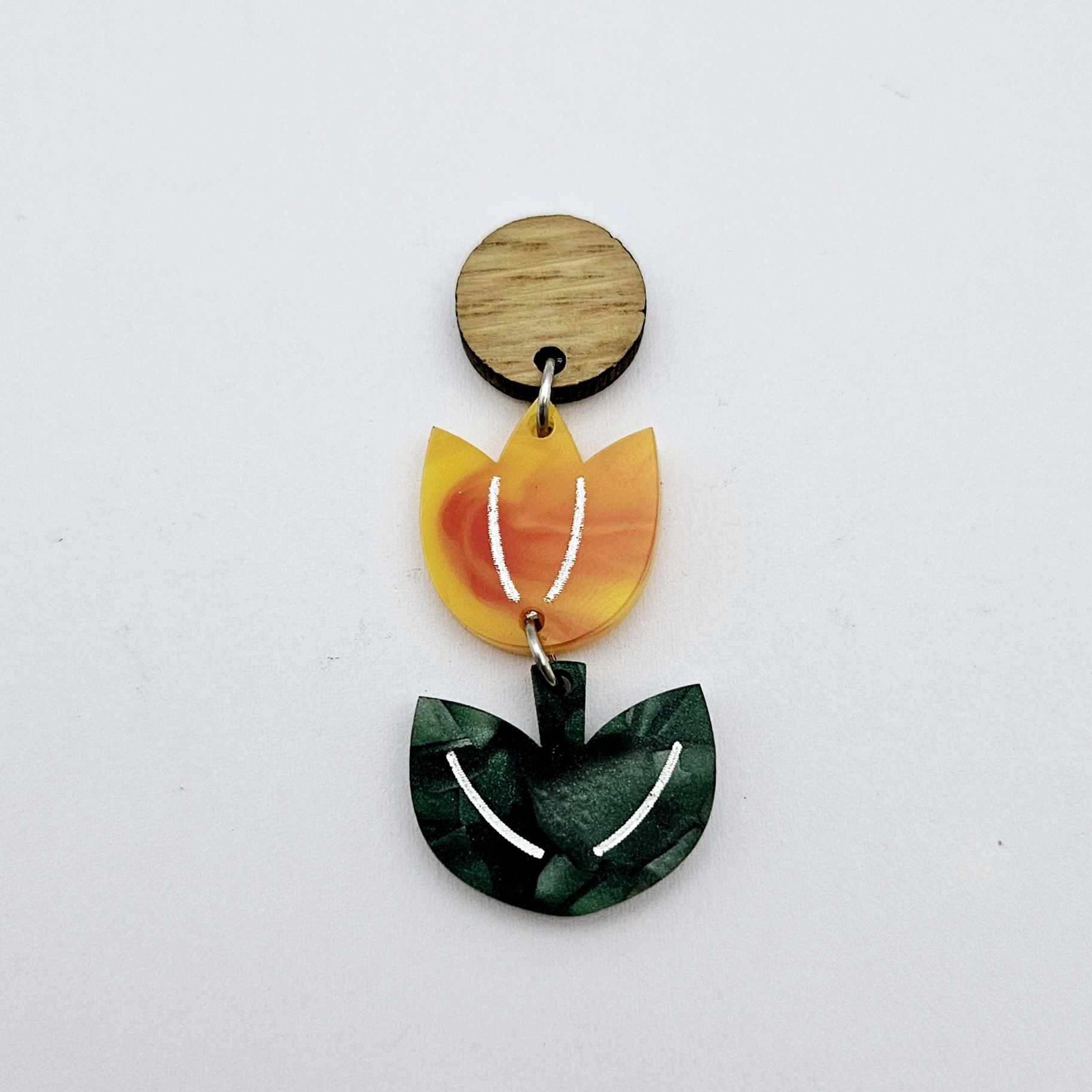 Assembled orange artist swirl and green mineral acrylic tulip dangle hanging from a 14mm oak wood topper, engraved detail paint filled white