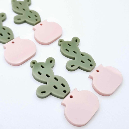 Two-piece cactus dangle blanks in olive green and strawberry milkshake pink, shown unassembled with cactus top and pot bottom pieces laid flat