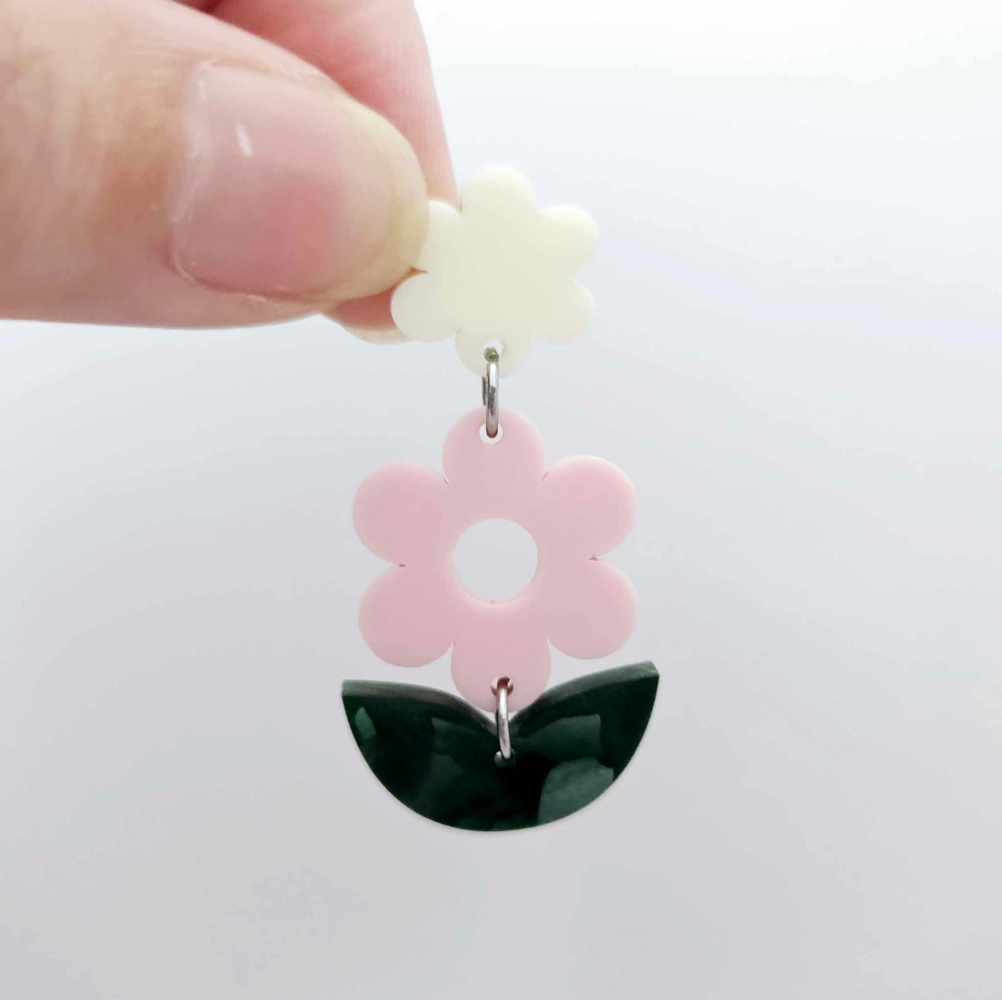 Assembled strawberry milkshake and green mineral acrylic flower dangle hanging from a cream flower topper, layered botanical earring design