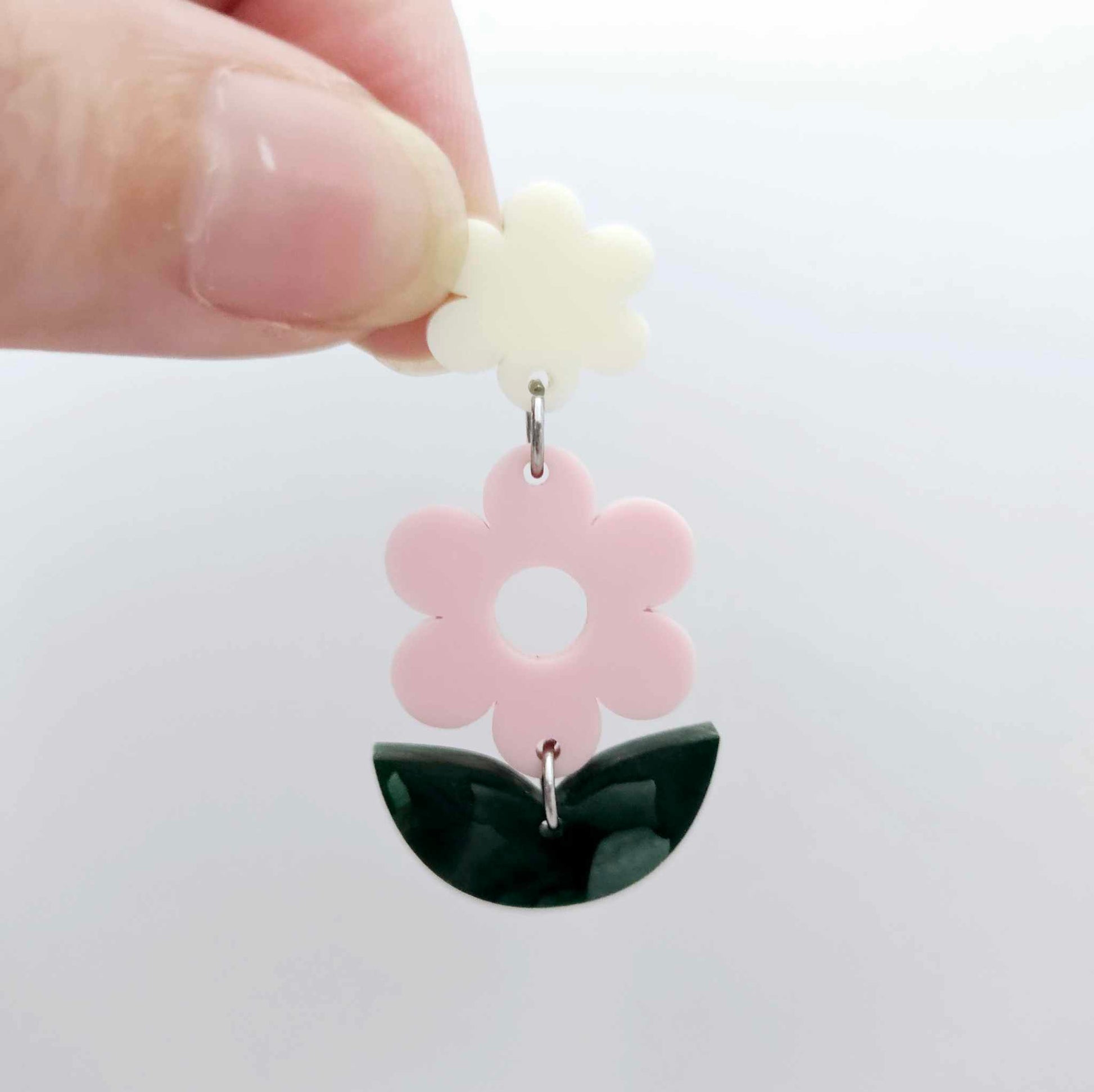 Assembled strawberry milkshake and green mineral acrylic flower dangle hanging from a cream flower topper, layered botanical earring design