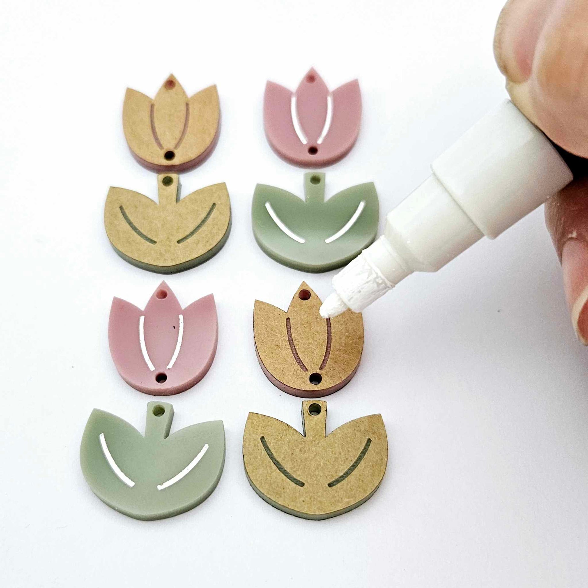 Two-piece tulip dangle blanks in dusty rose and olive green, paint filled white on one pair with remaining pair unfilled, shown with a white Posca paint pen