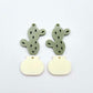 Two-piece acrylic cactus dangle blanks in olive green and cream, shown unassembled with cactus top and pot bottom pieces laid flat