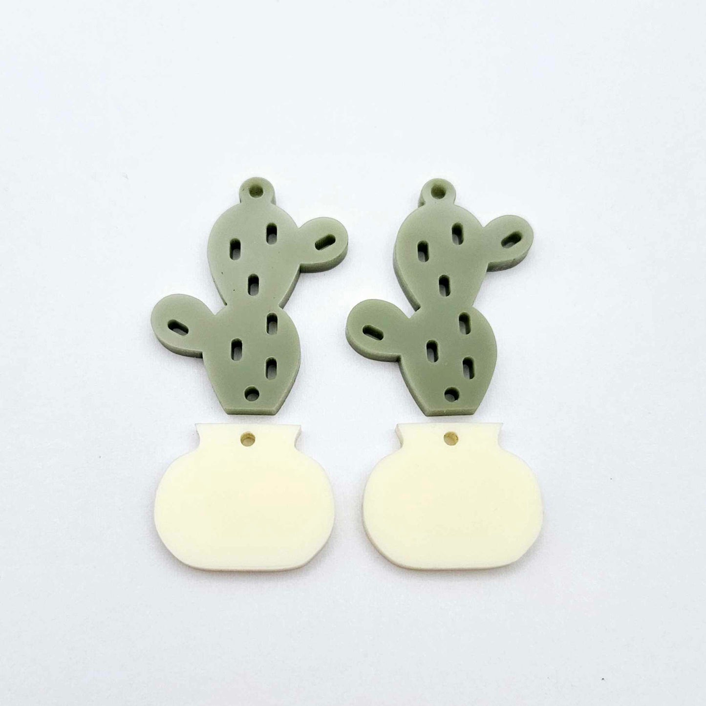 Two-piece acrylic cactus dangle blanks in olive green and cream, shown unassembled with cactus top and pot bottom pieces laid flat