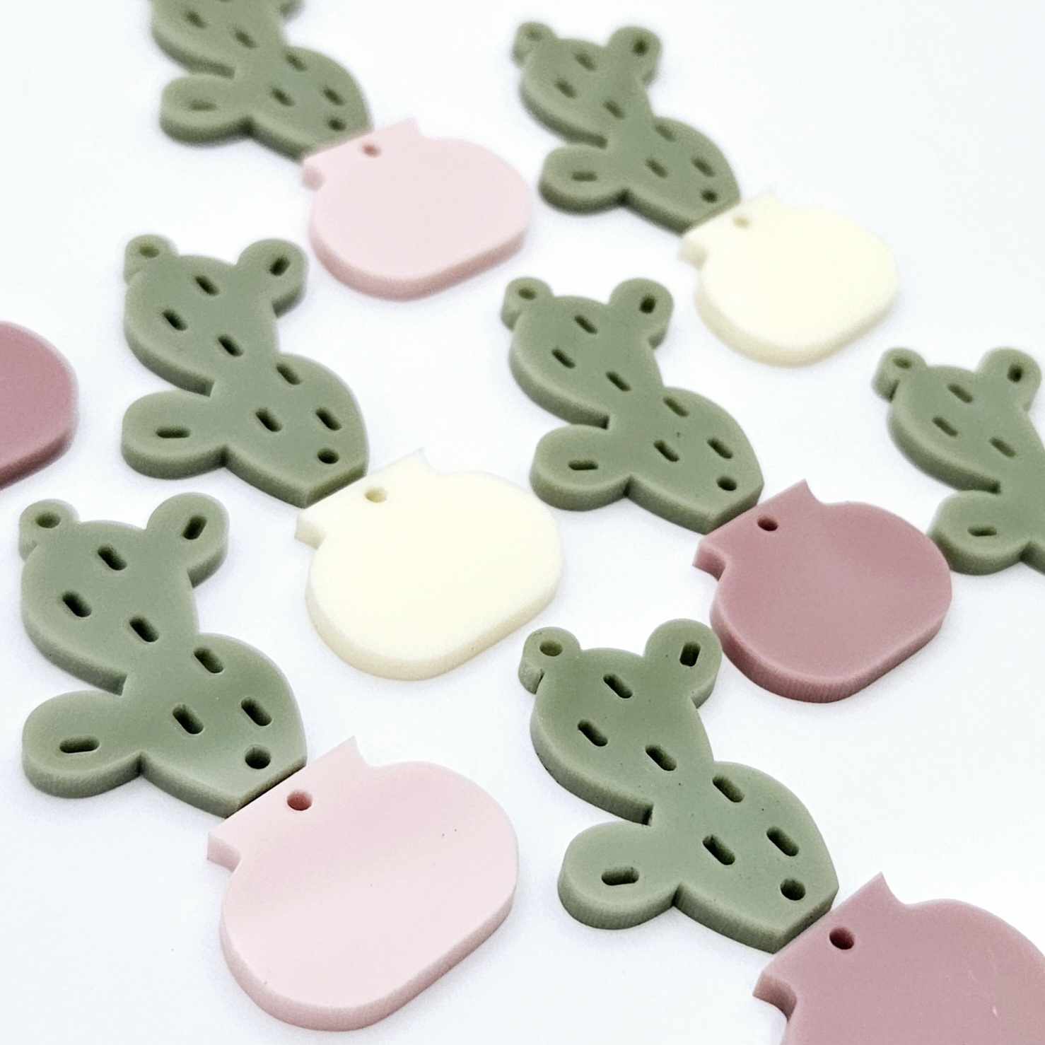 Two-piece acrylic cactus dangle blanks in olive green with mixed coloured pots, shown unassembled with cactus top and pot bottom pieces laid flat