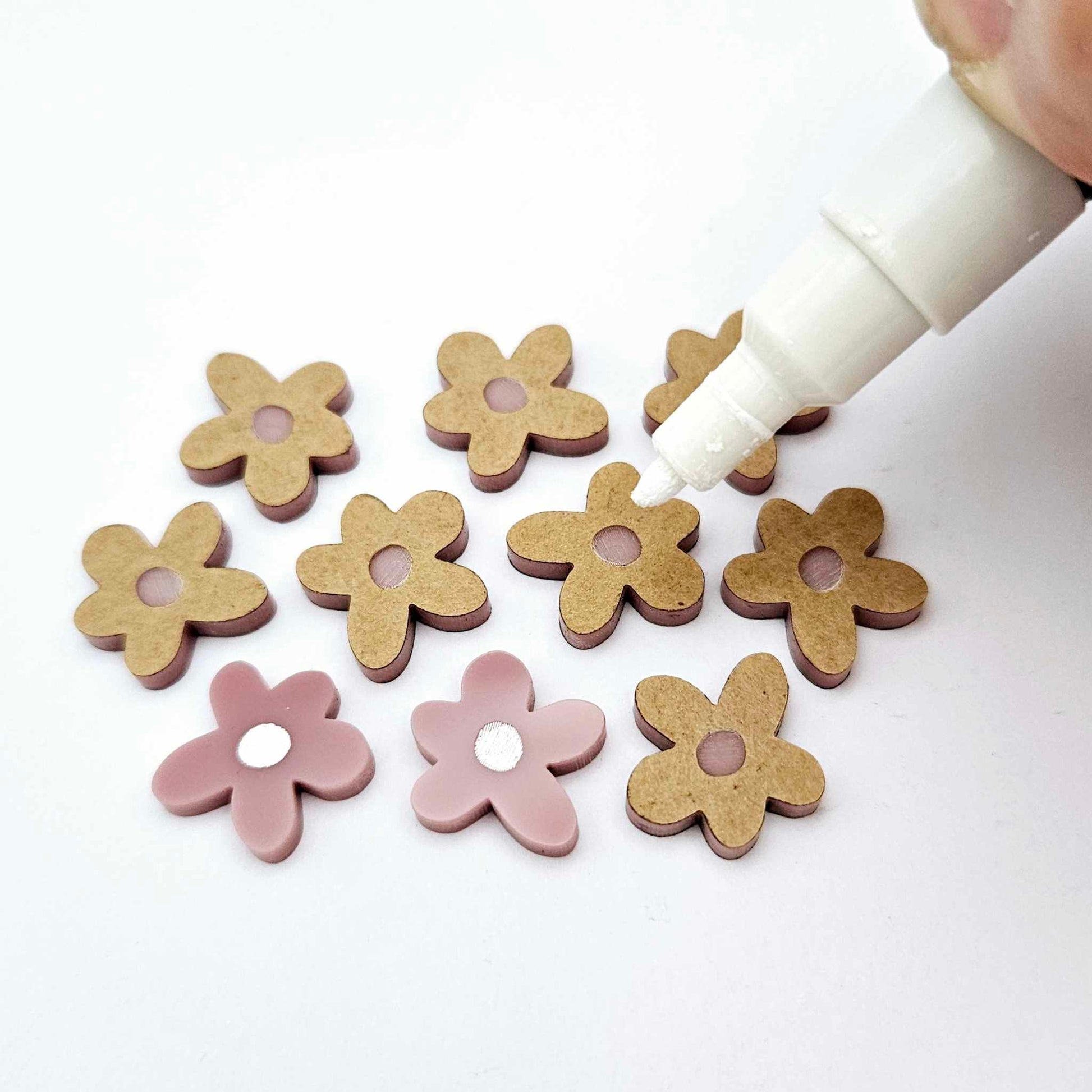 16mm dusty rose organic flower stud blanks showing paint filled white example and unfilled pieces with protective film, pictured with a white Posca paint pen
