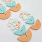 Three-piece acrylic flower dangle blanks shown unassembled laying flat, featuring Floral Bloom UV printed flower, aqua leafy middle and orange leafy bottom