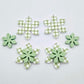 Green gingham UV print and pastel green acrylic two layer flower dangle blanks shown laying flat, with some flowers stacked to show layered effect and others positioned side by side