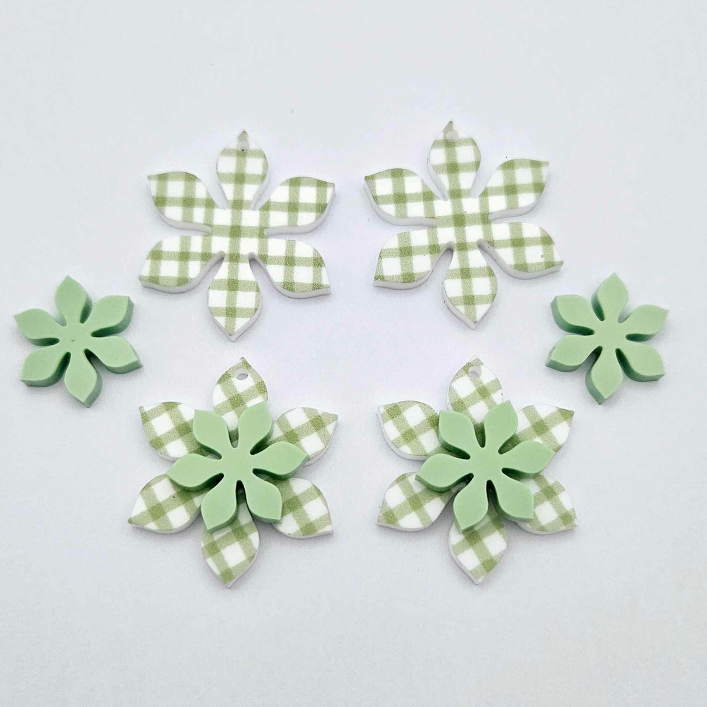 Green gingham UV print and pastel green acrylic two layer flower dangle blanks shown laying flat, with some flowers stacked to show layered effect and others positioned side by side