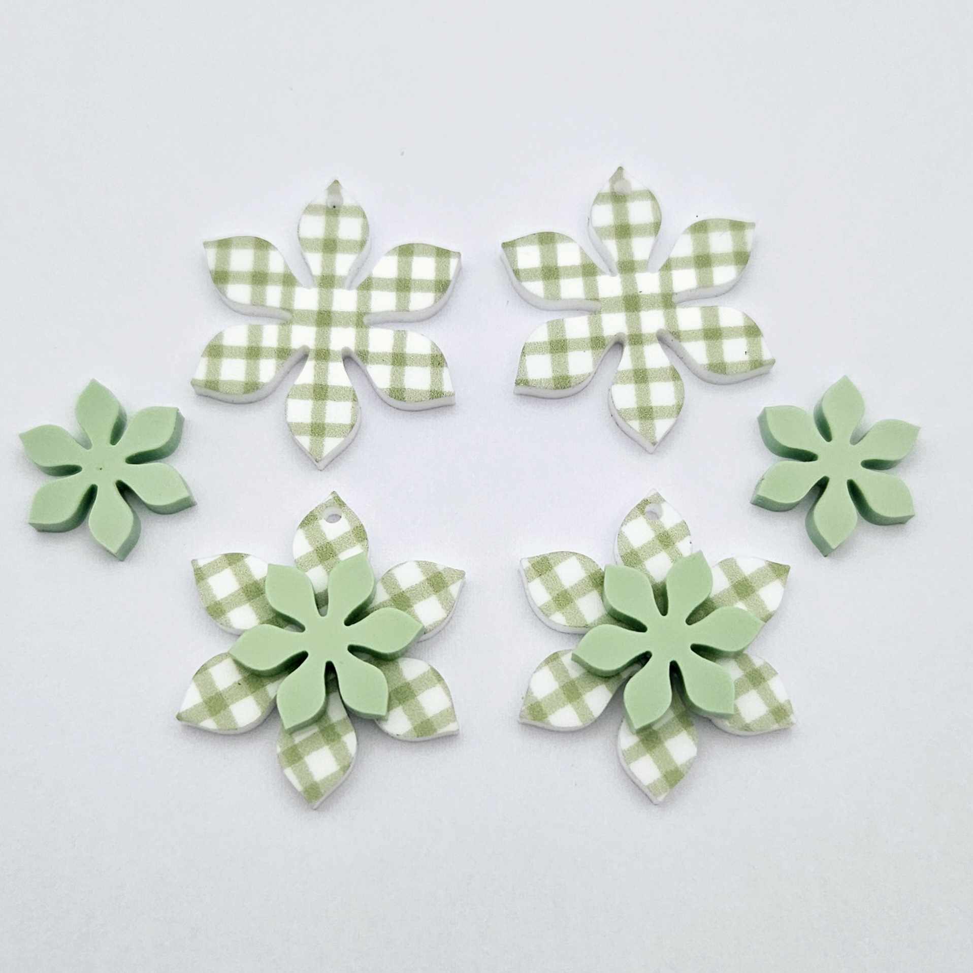 Green gingham UV print and pastel green acrylic two layer flower dangle blanks shown laying flat, with some flowers stacked to show layered effect and others positioned side by side