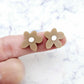 Two 16mm iced coffee brown organic flower stud blanks with engraved centre paint filled white, shown on a finger for size reference