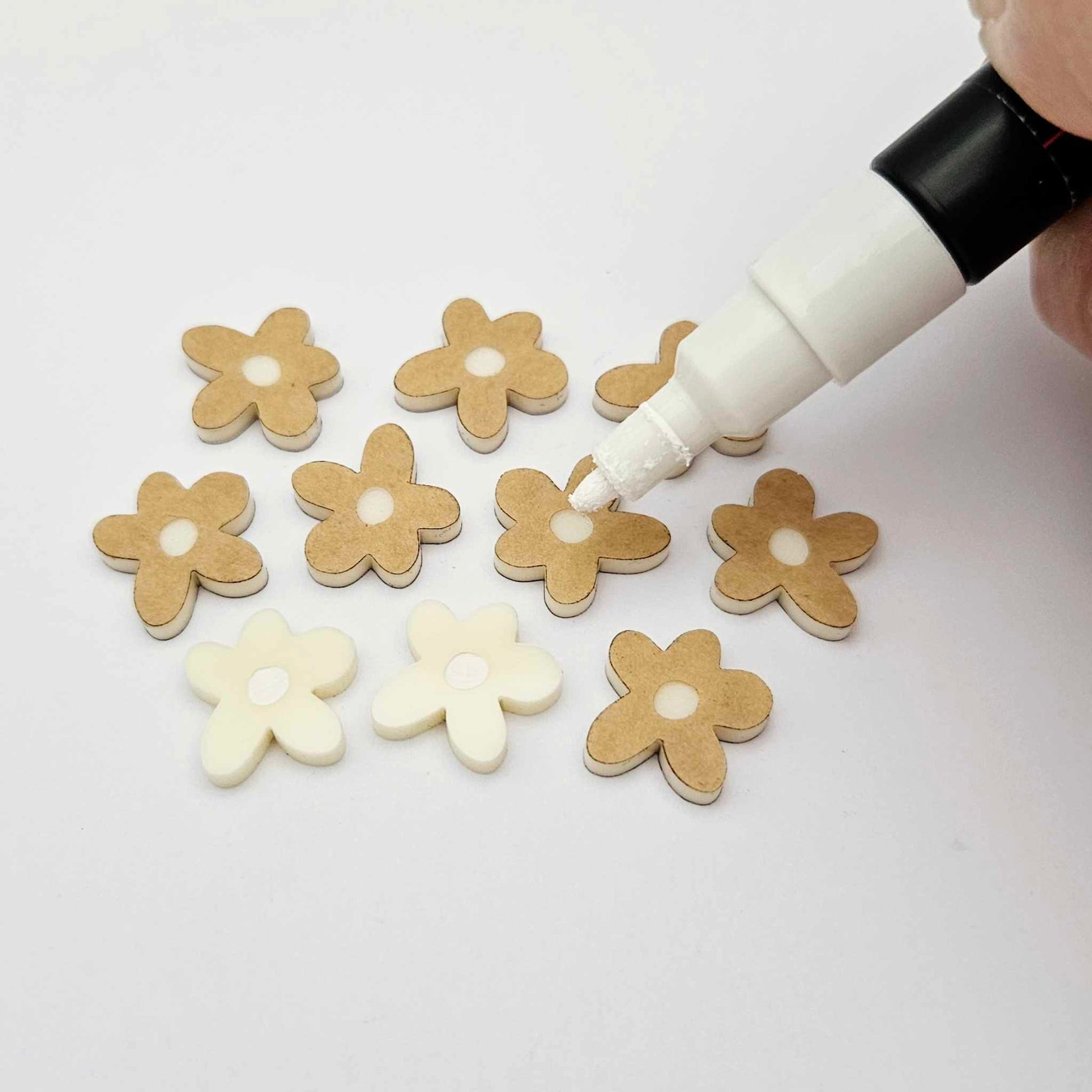 16mm cream organic flower stud blanks showing paint filled white example and unfilled pieces with protective film, pictured with a white Posca paint pen