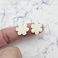 Two 14mm cream acrylic flower stud blanks, shown on a finger for size reference