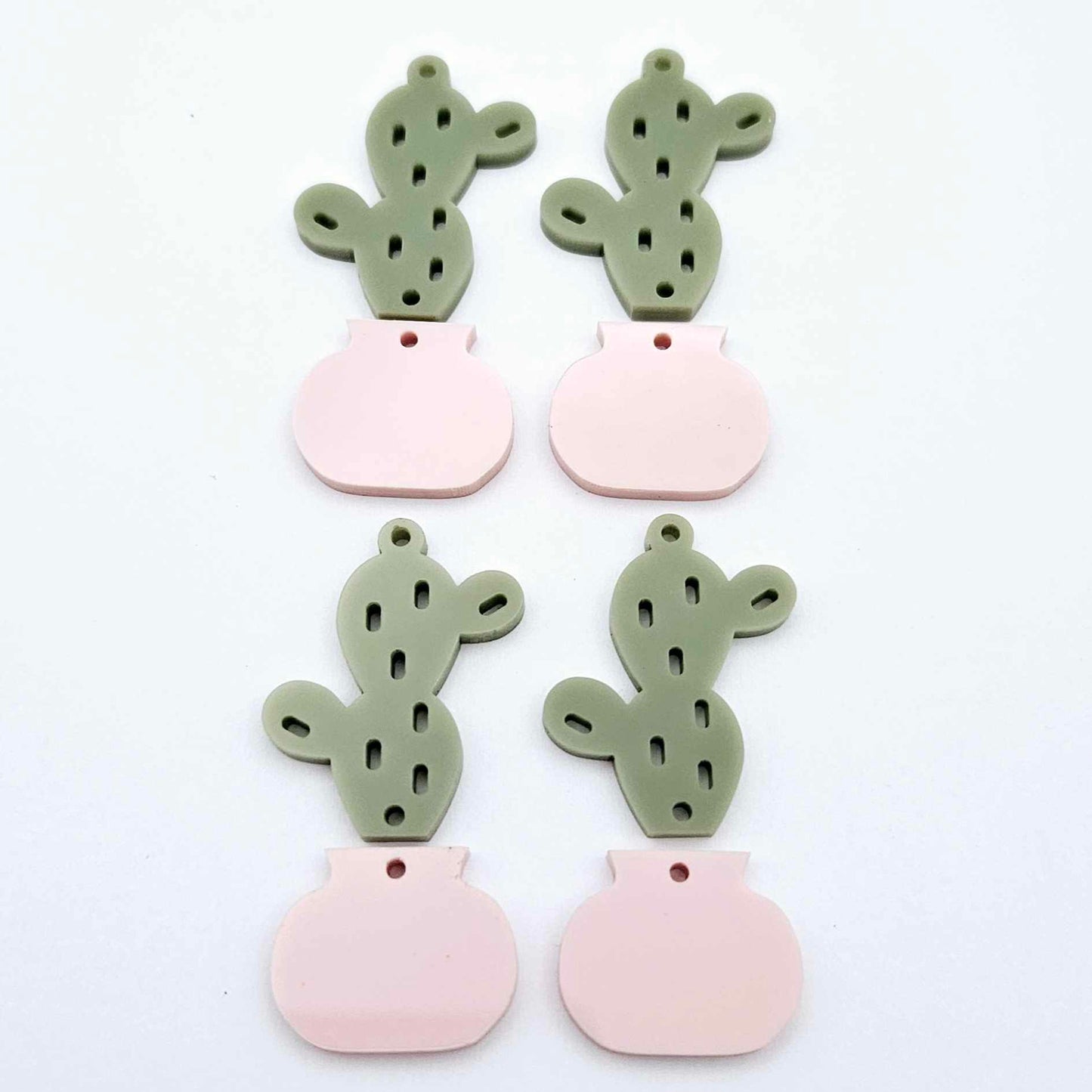 Two-piece cactus dangle blanks in olive green and strawberry milkshake pink, shown unassembled with cactus top and pot bottom pieces laid flat