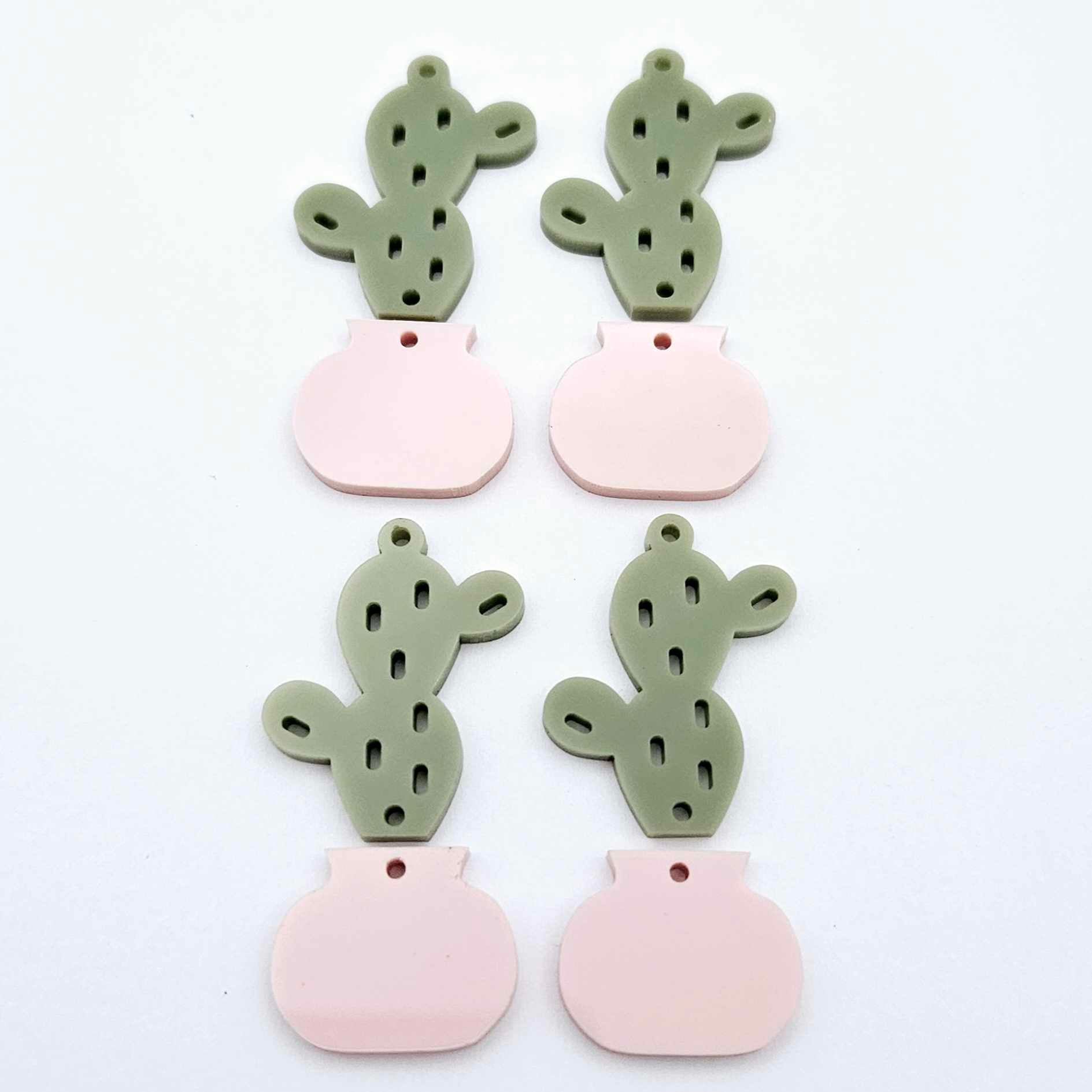 Two-piece cactus dangle blanks in olive green and strawberry milkshake pink, shown unassembled with cactus top and pot bottom pieces laid flat