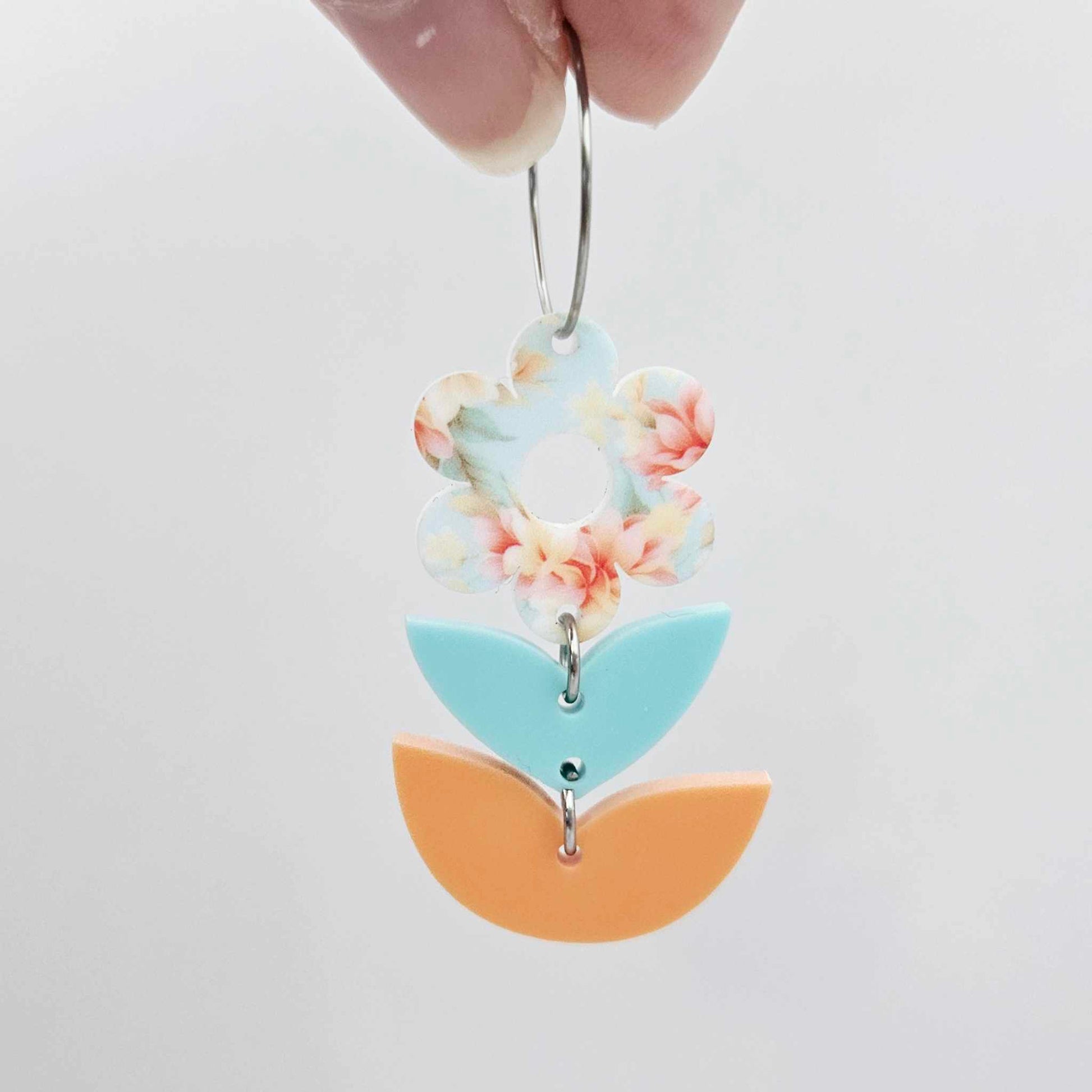 Assembled three-piece acrylic flower dangle hanging from a 20mm hoop, UV printed Floral Bloom flower with aqua and orange leaf layers