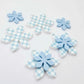 Blue gingham UV print and pastel blue acrylic two layer flower dangle blanks shown laying flat, with some flowers stacked to show layered effect and others positioned side by side